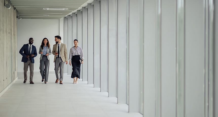 Four colleagues walking together down a bright corridor